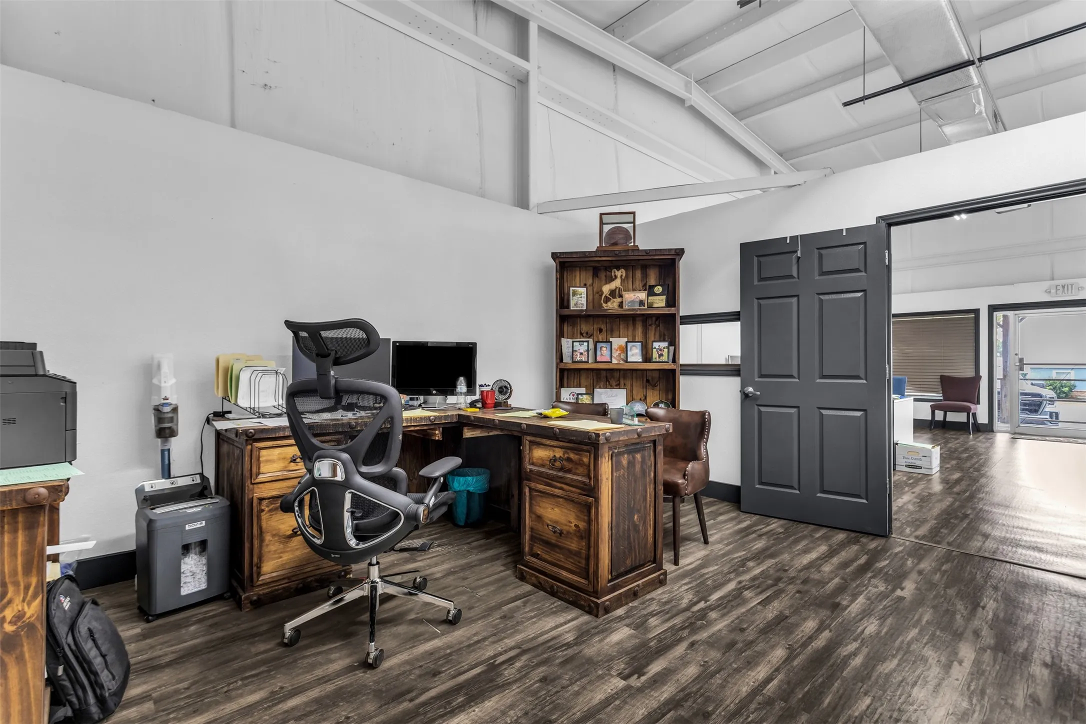Spacious room featuring laminate flooring and a door to the adjacent office area