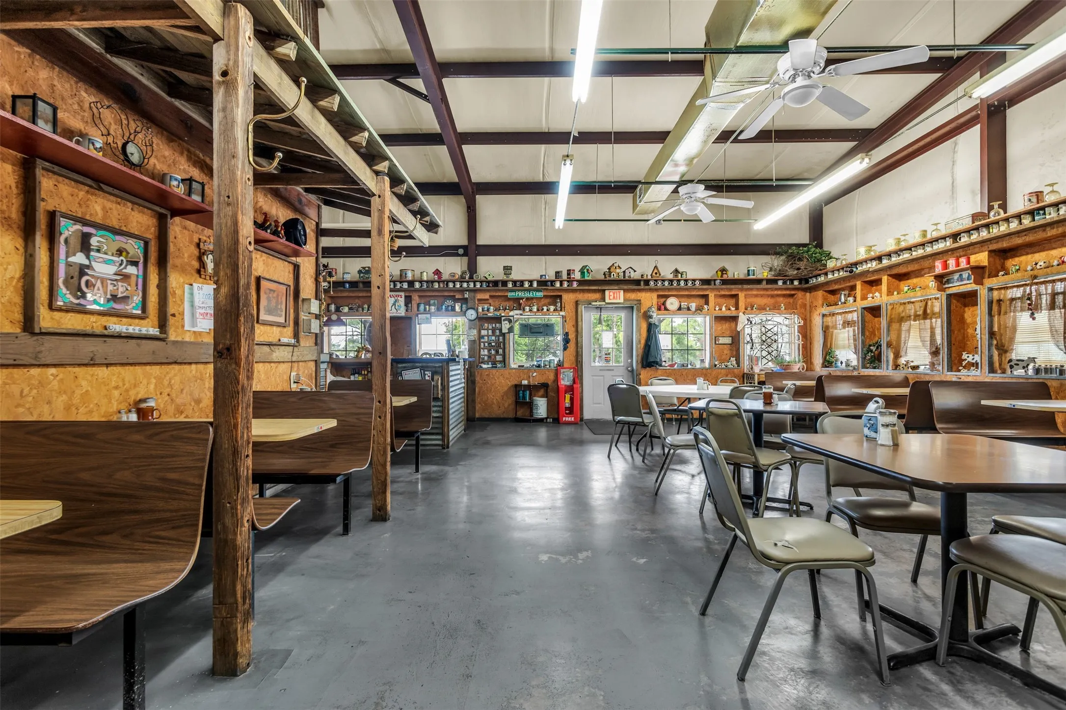 Spacious interior featuring a concrete floor, exposed structural beams, and wood-paneled walls