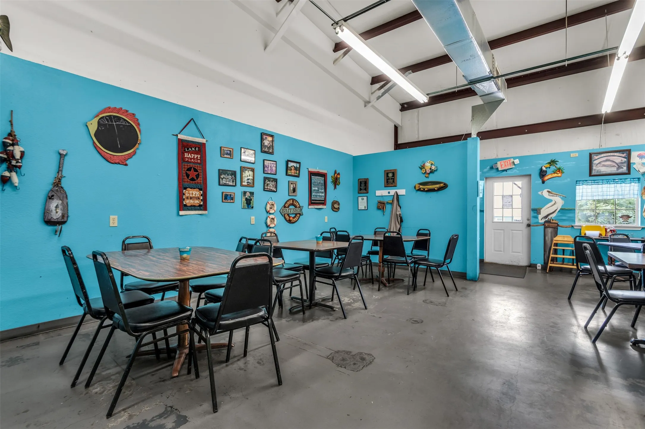 Open-concept interior featuring a concrete floor, exposed ceiling beams, and fluorescent strip lighting