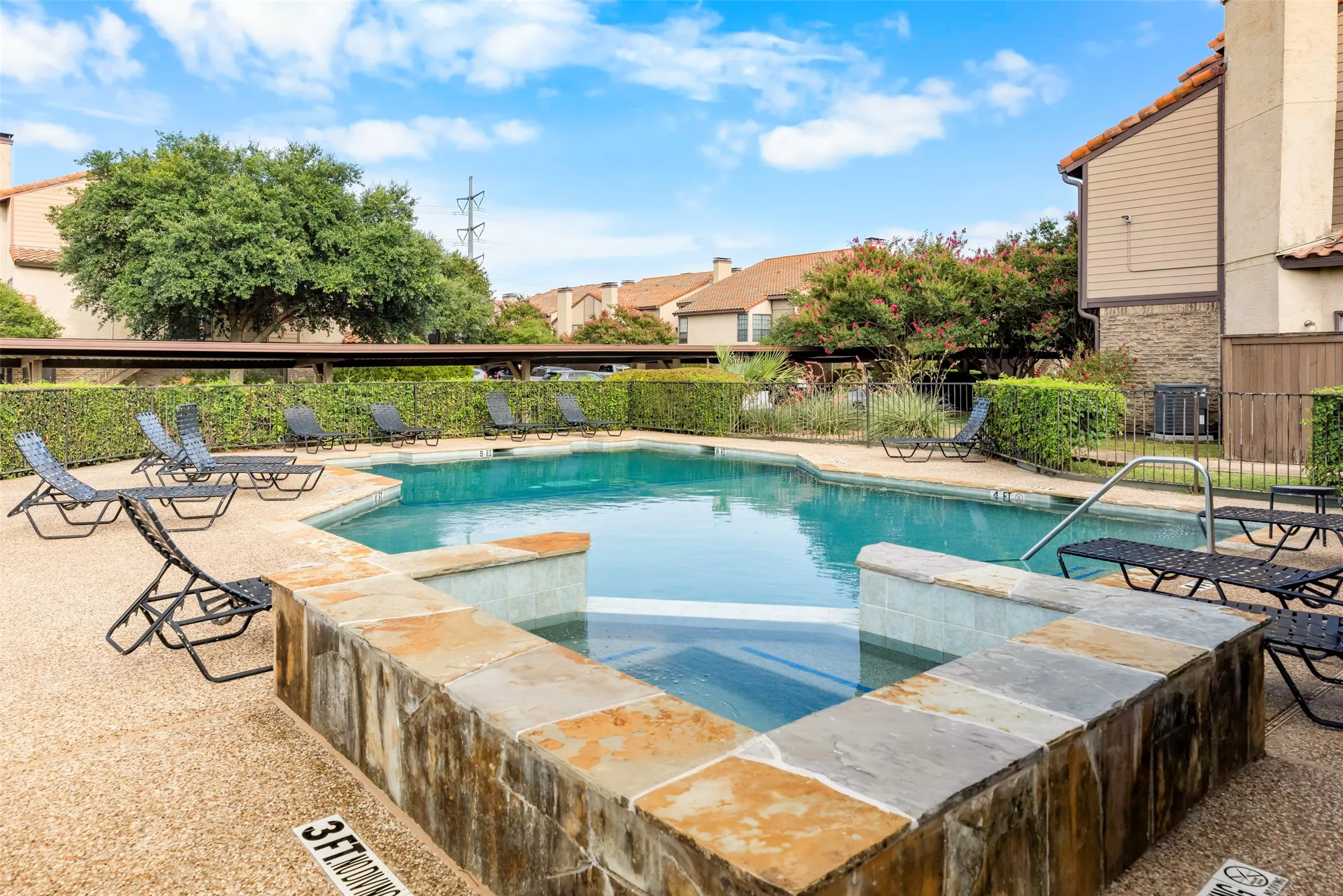 Resort-style pool area featuring a built-in spa, flagstone coping, and a surrounding aggregate deck