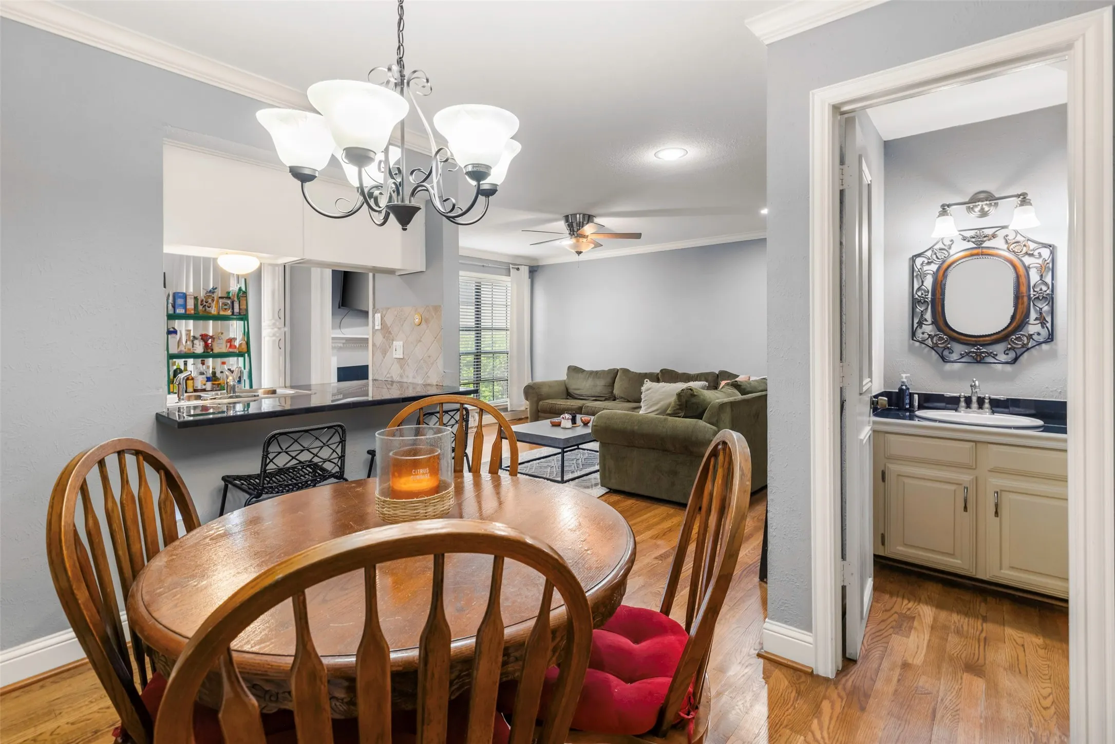 Dining area featuring a decorative chandelier, wood-finish flooring, a pass-through counter, and crown molding