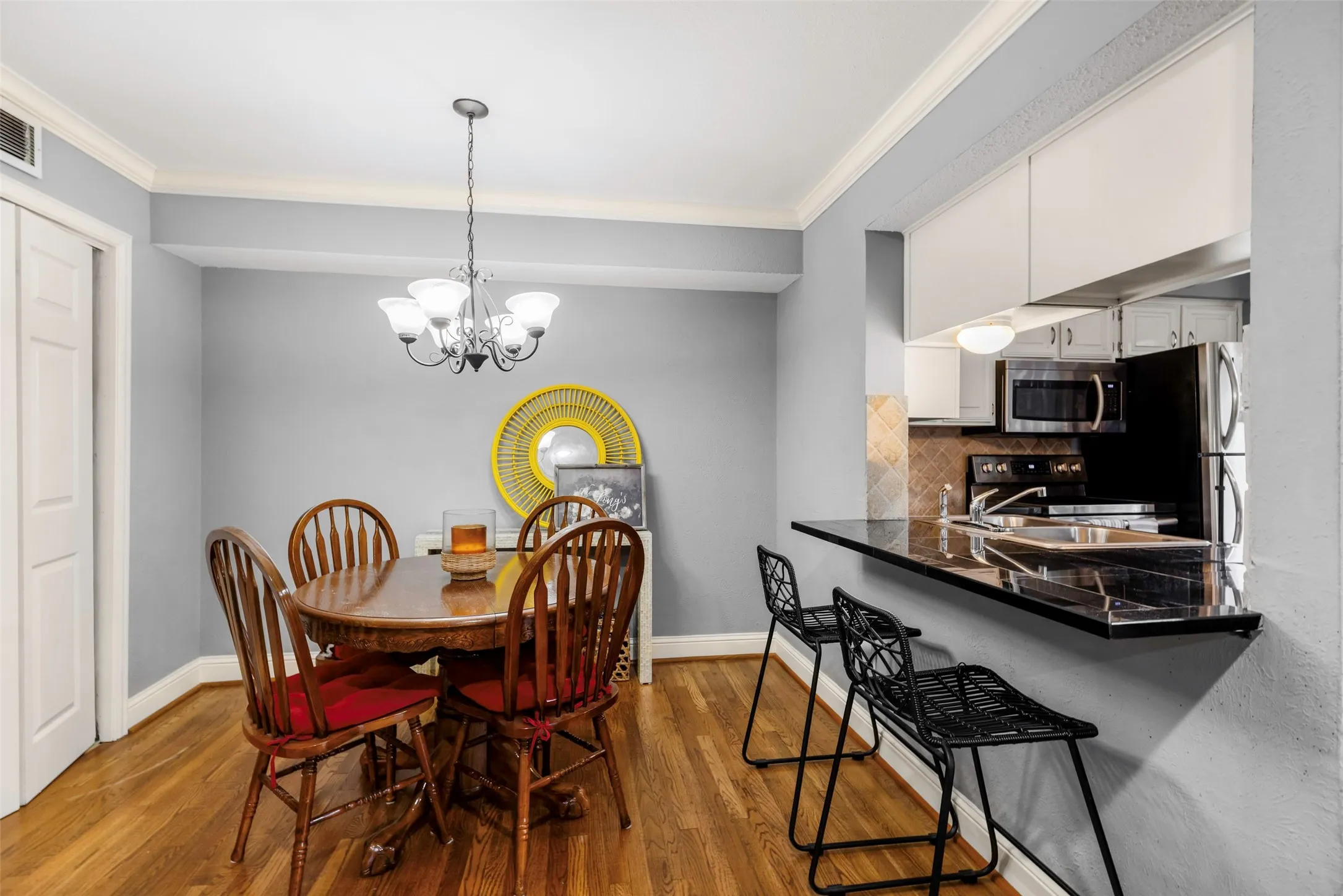 Dining area featuring wood-finish flooring, a contemporary chandelier, and crown molding