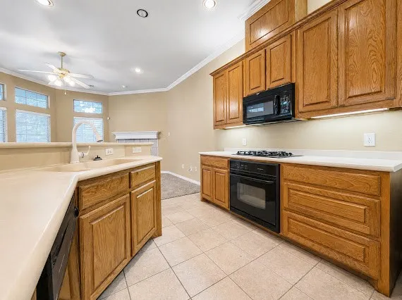 Kitchen featuring wood-finish cabinetry, light-toned countertops, and tile flooring