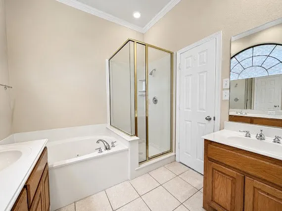 Bathroom featuring a corner soaking tub, a stand-up shower with a glass enclosure, and dual vanity sinks with wood-finish cabinetry