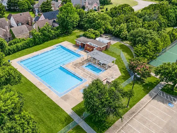 Swimming pool area featuring a large lap pool, a smaller wading pool with a pergola, and surrounding concrete decking