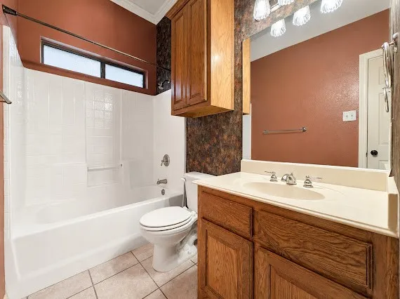 Bathroom featuring a white bathtub, ceramic tile flooring, wood-finish vanity with an integrated sink, surface-mounted lighting, and an upper wood-finish cabinet