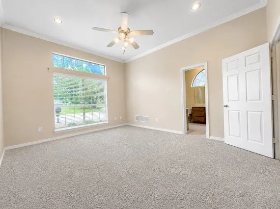 Expansive room featuring light-toned carpeting, vaulted ceiling, and crown molding