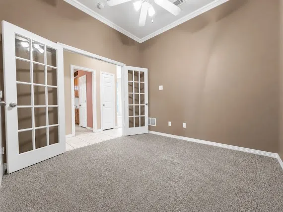 Room featuring French doors, carpeted flooring, vaulted ceiling, crown molding, and a ceiling fan with light fixture