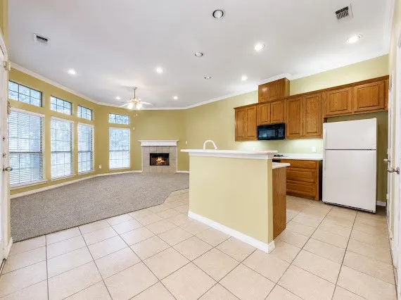 Open-concept living space featuring a kitchen with wood cabinetry, a built-in microwave, and a white refrigerator