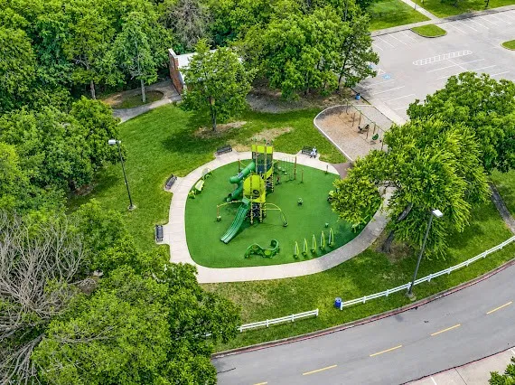 Recreational park area featuring a multi-level playground structure, swing set, outdoor fitness equipment, and dedicated soft-surface play zones