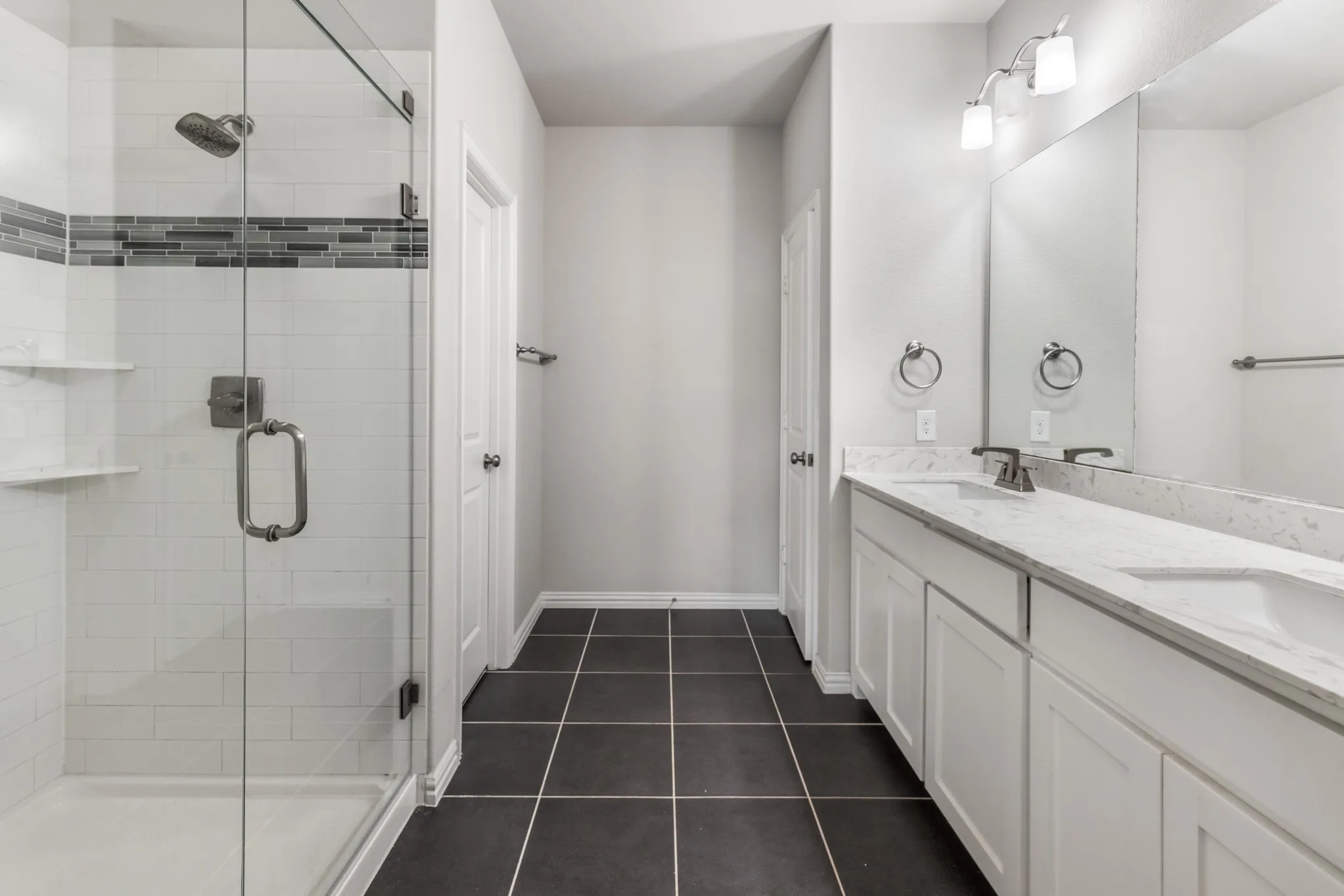 Shower with glass enclosure, subway tile surround, and decorative mosaic accent