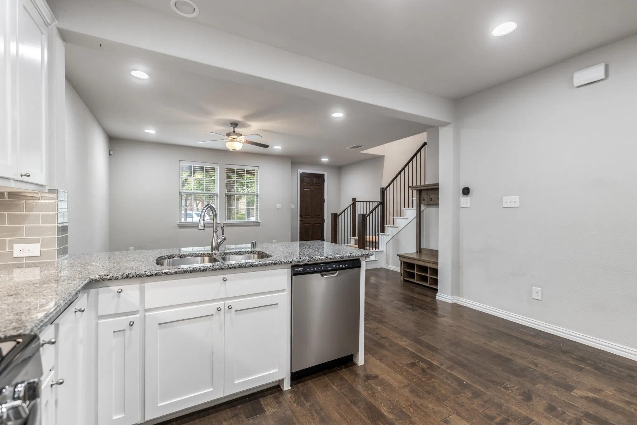 Kitchen island with a double basin sink, granite countertop, and stainless steel dishwasher