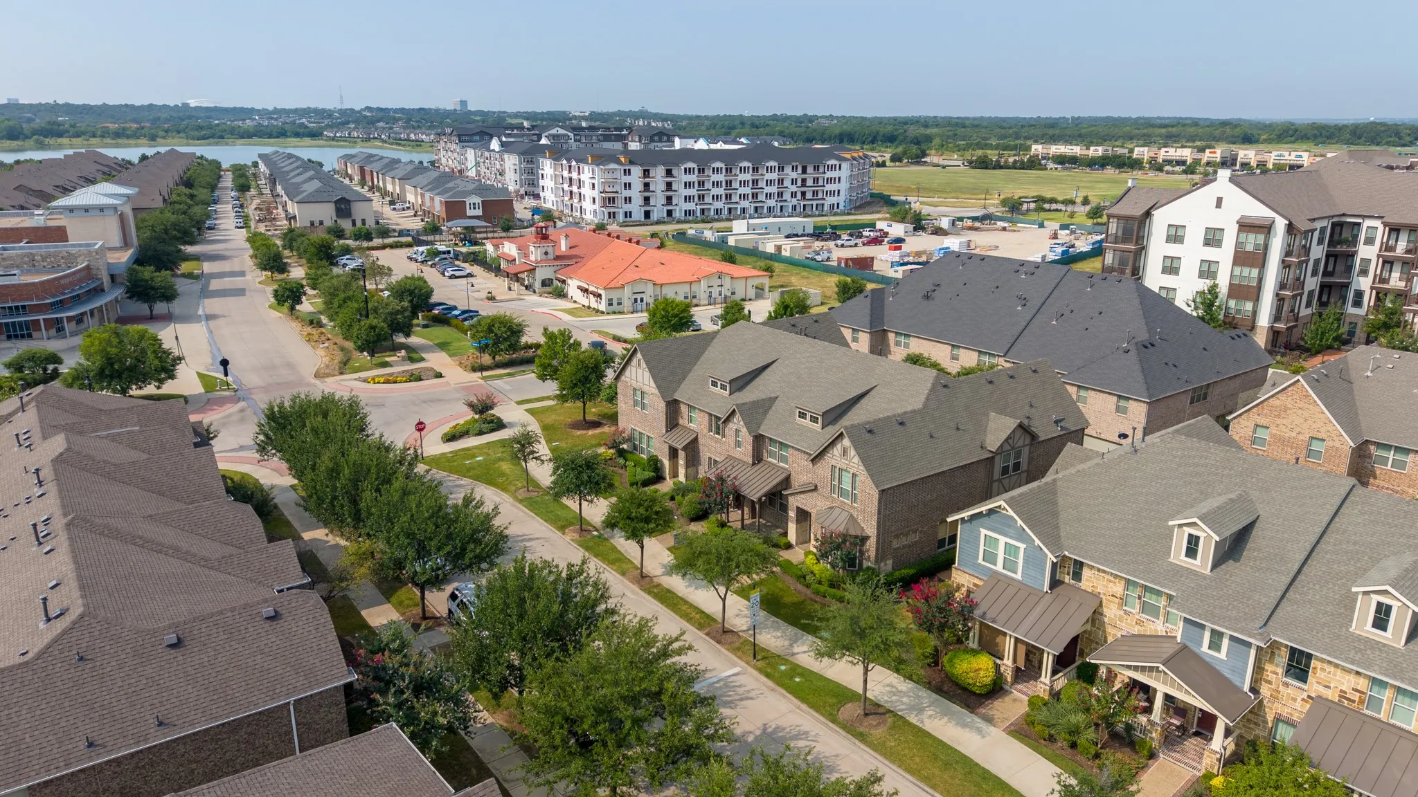 Aerial perspective of a mixed-use development featuring residential properties, commercial buildings, and multi-story apartment complexes