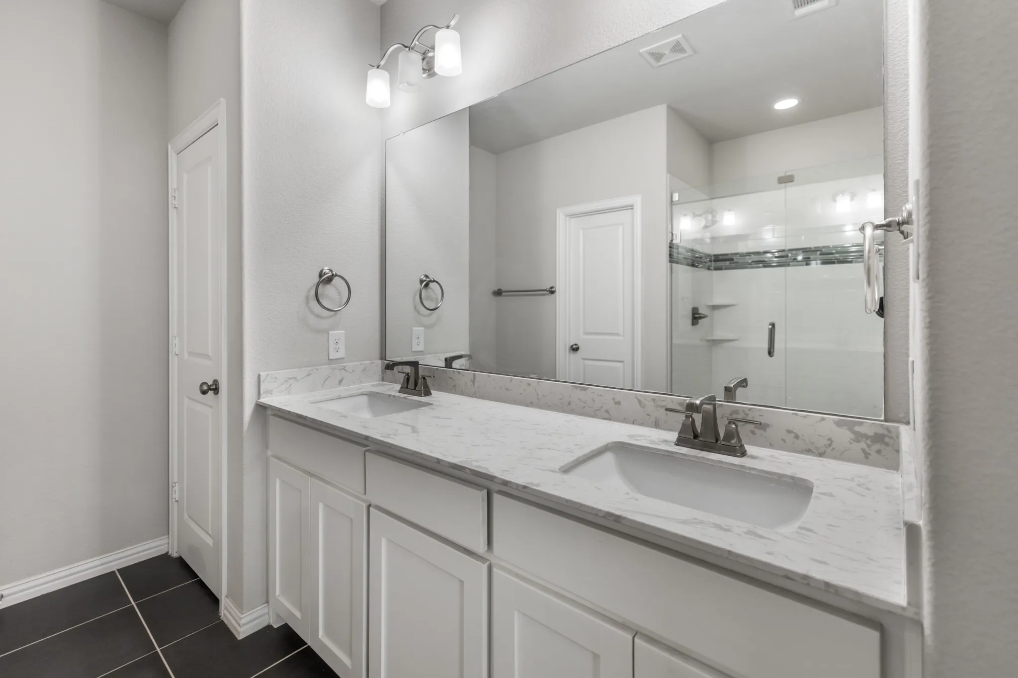 Double vanity with white shaker-style cabinetry and a light-toned countertop