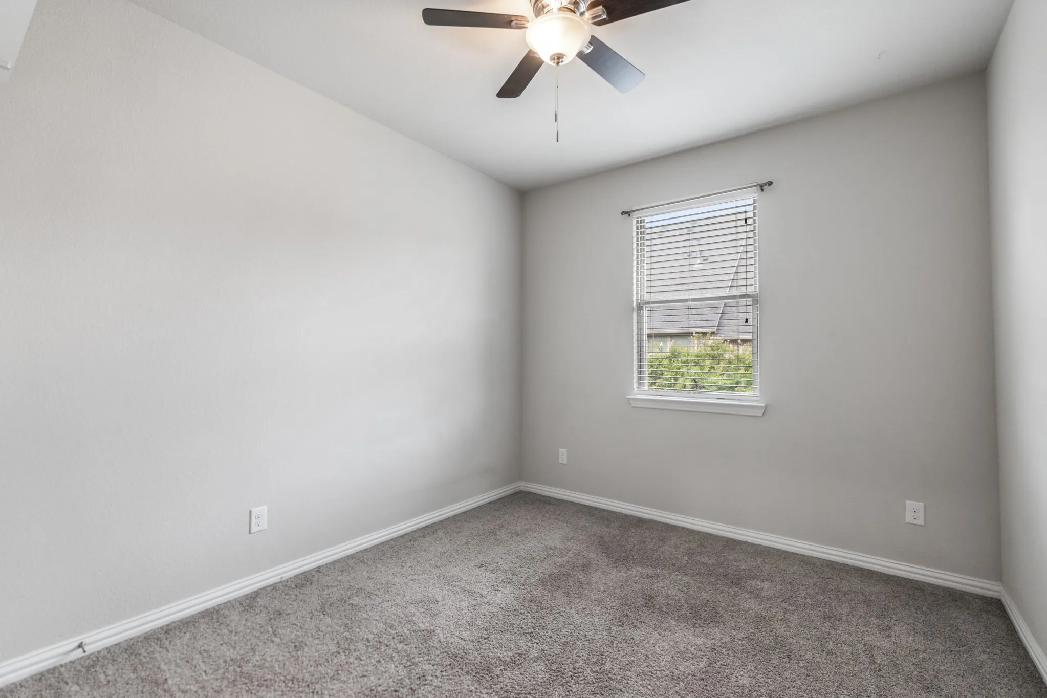Carpeted room featuring a single window with blinds, a ceiling fan with integrated lighting, and neutral wall tones