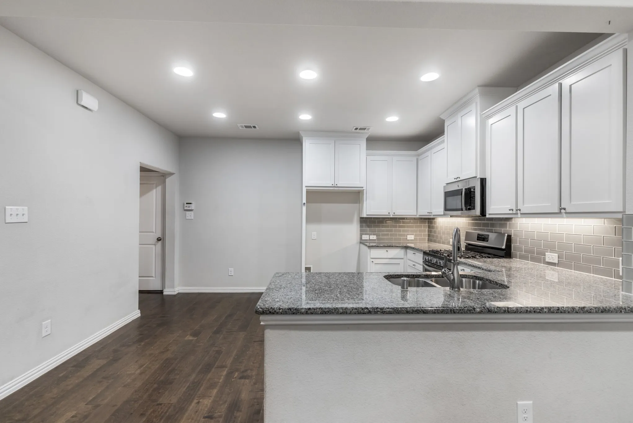 Modern kitchen featuring white cabinetry, stainless steel appliances, a tile backsplash, and stone countertops