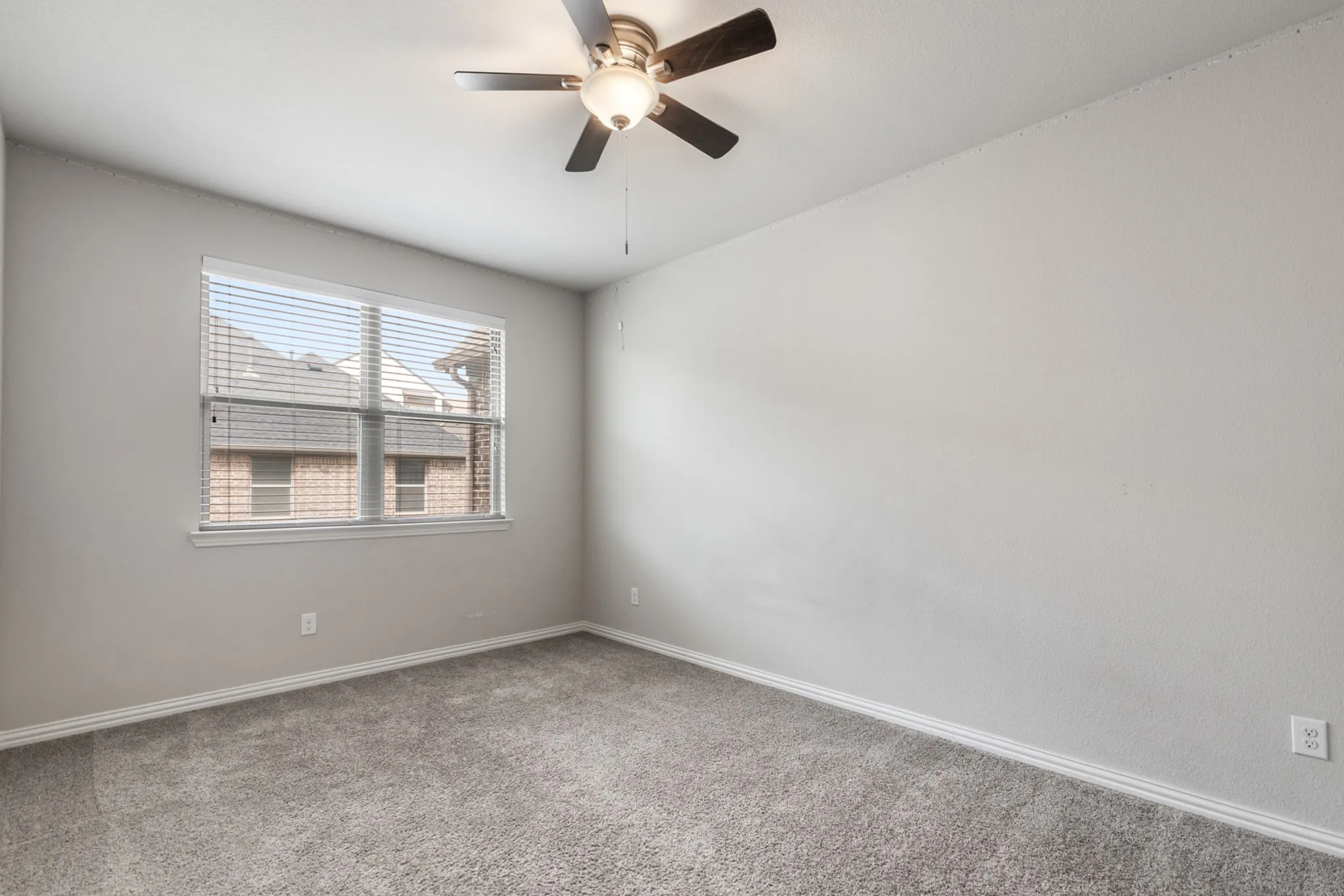Spacious room featuring neutral grey carpeting and light grey wall paint