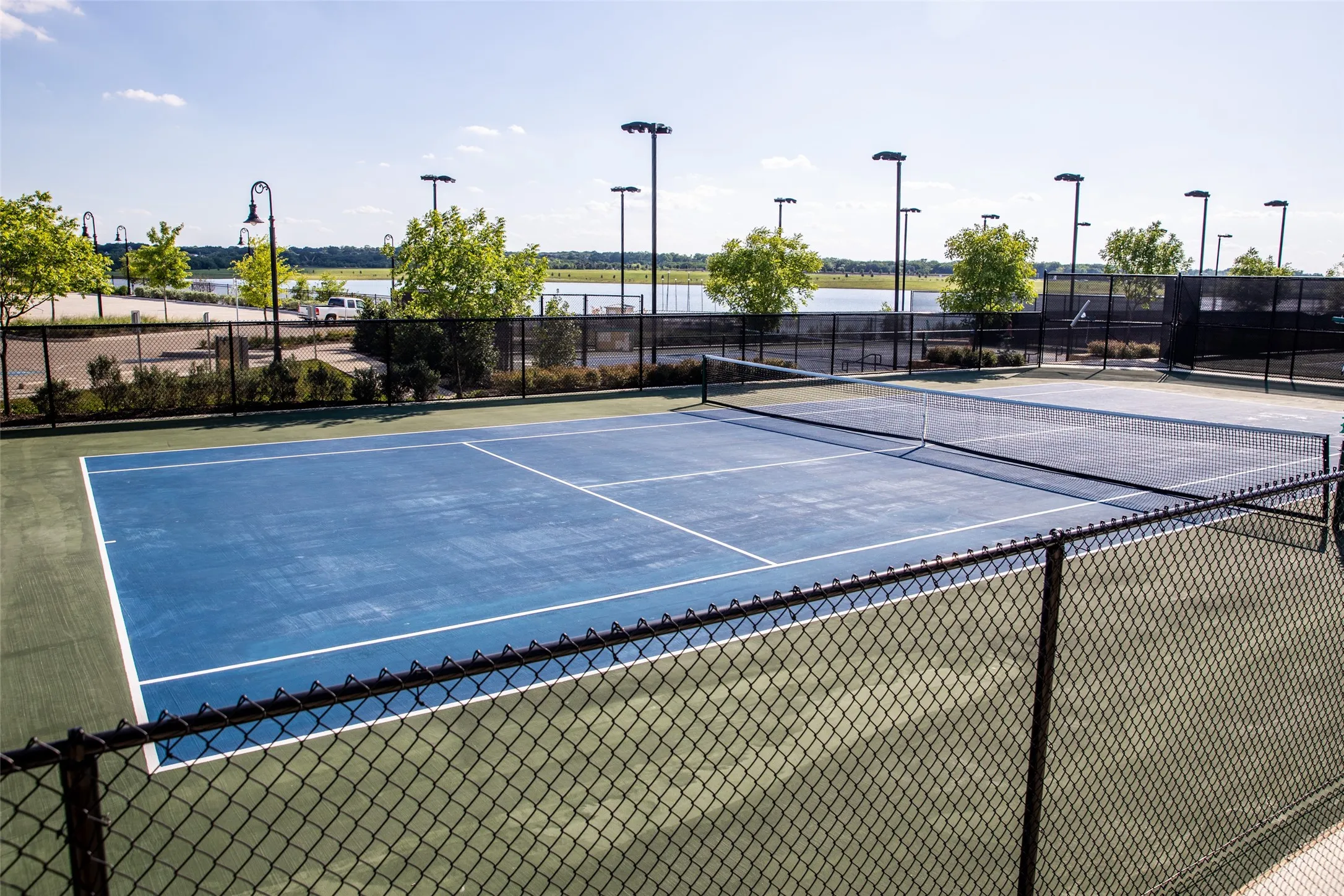 Hard surface tennis courts featuring perimeter fencing and court lighting