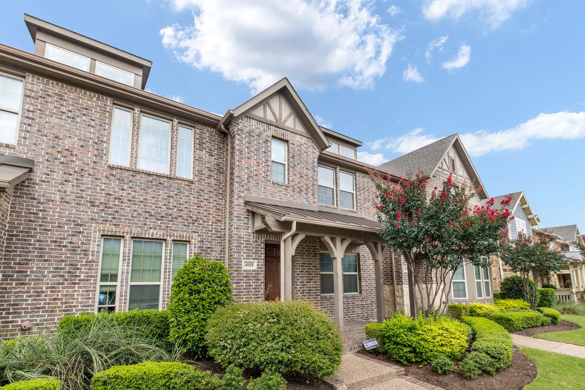 Traditional brick townhouse with gabled roofline, decorative timber accents, and covered entry porch