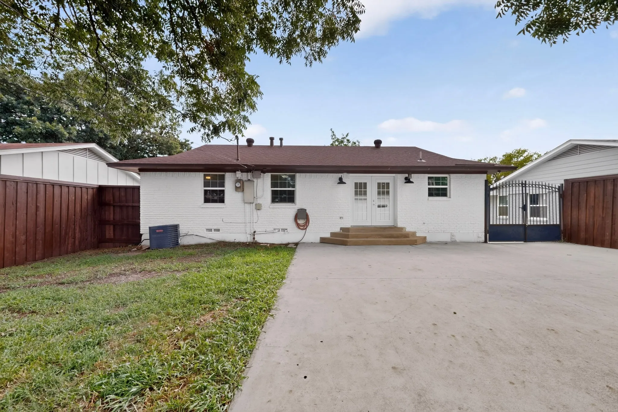 Rear exterior featuring white brick siding and a brown shingle roof