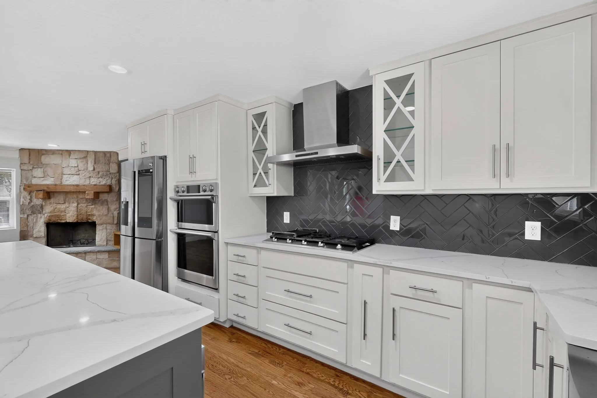 Kitchen featuring white shaker cabinetry, stainless steel appliances, a herringbone tile backsplash, and light-toned countertops