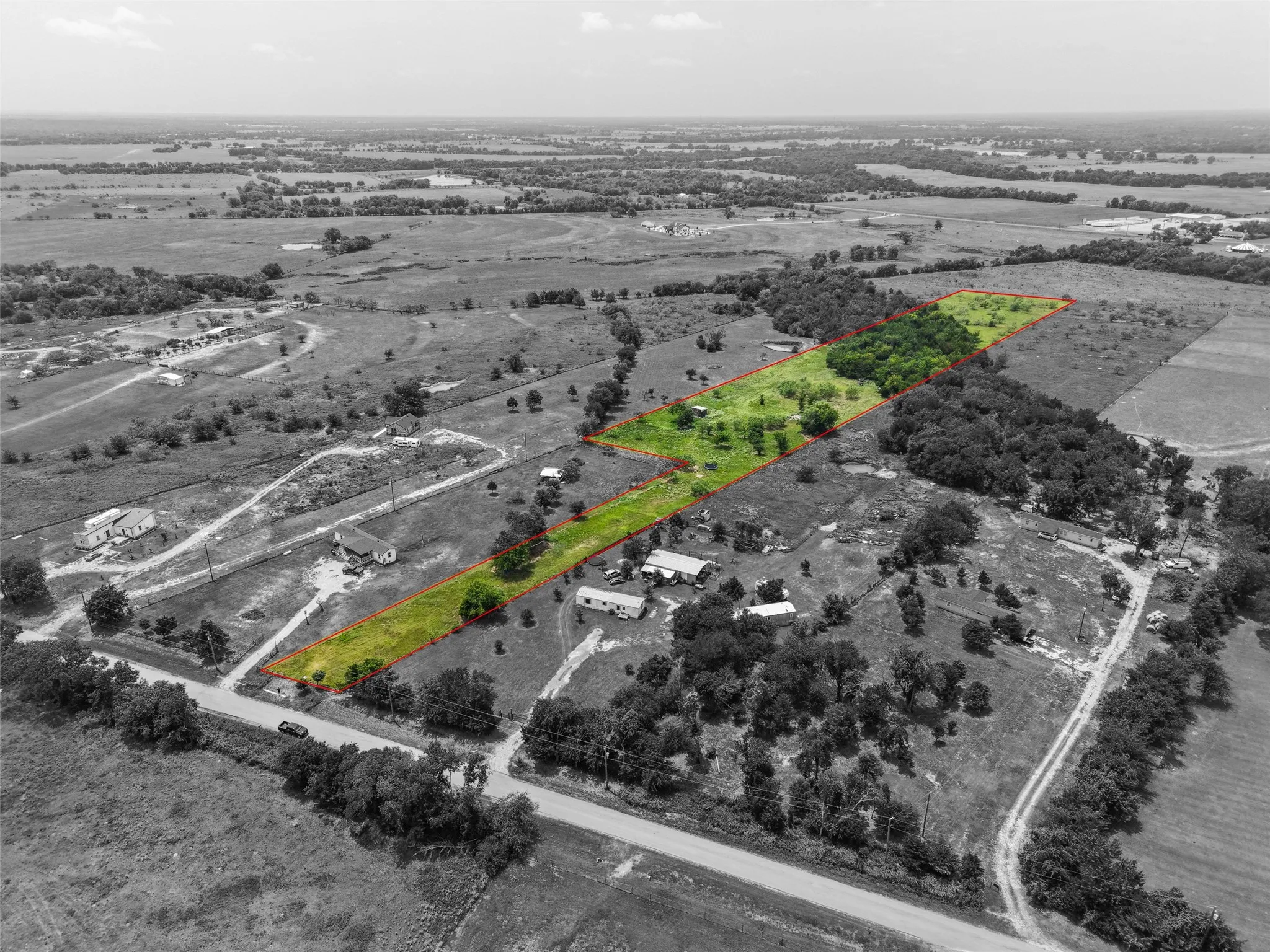 Expansive undeveloped land parcel featuring a rectangular shape and partial tree coverage