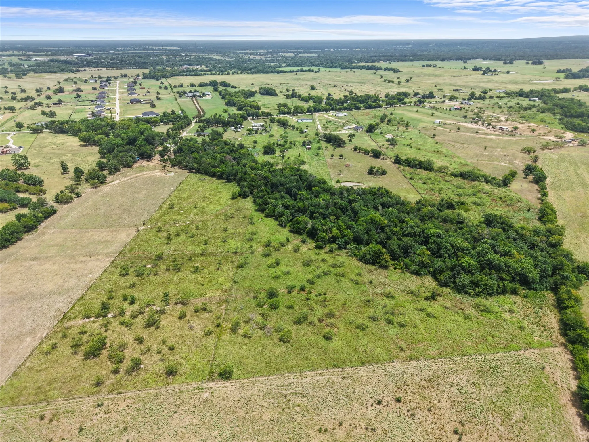 Expansive rural acreage featuring a mix of open fields and mature tree lines