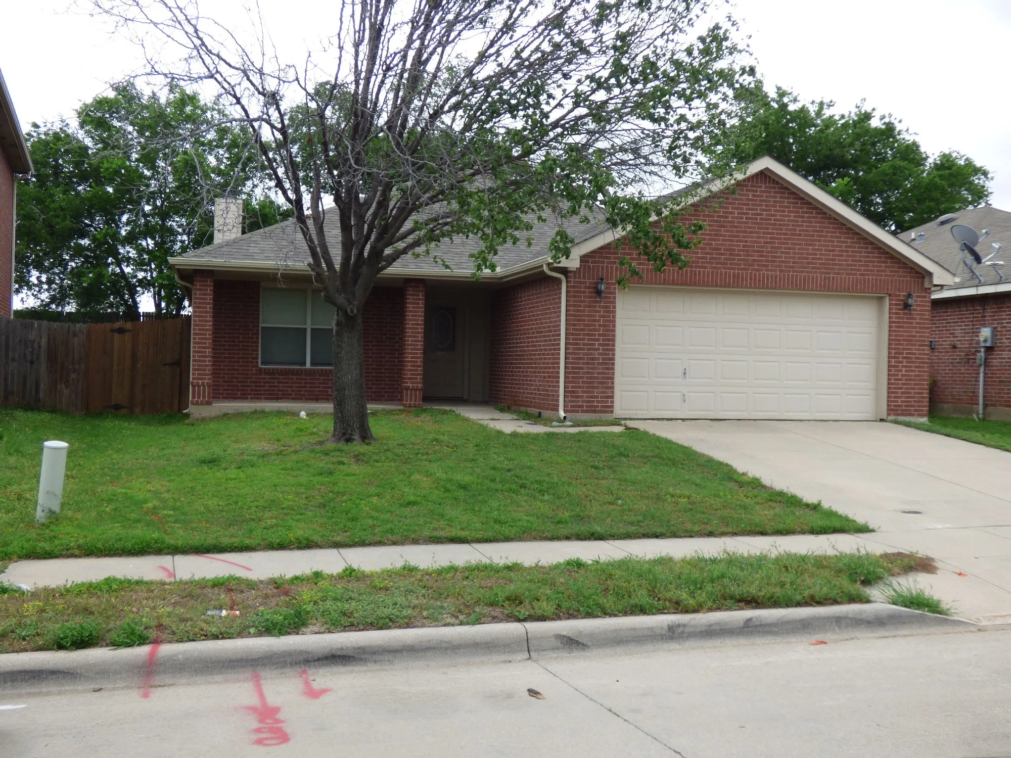 Brick exterior with an attached two-car garage, concrete driveway, and front lawn