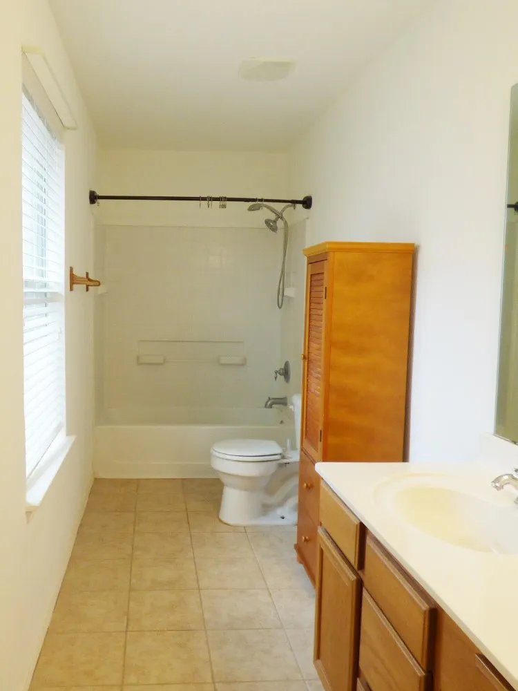Bathroom with ceramic tile flooring, a bathtub-shower combination, and a single vanity with wood-finish cabinetry