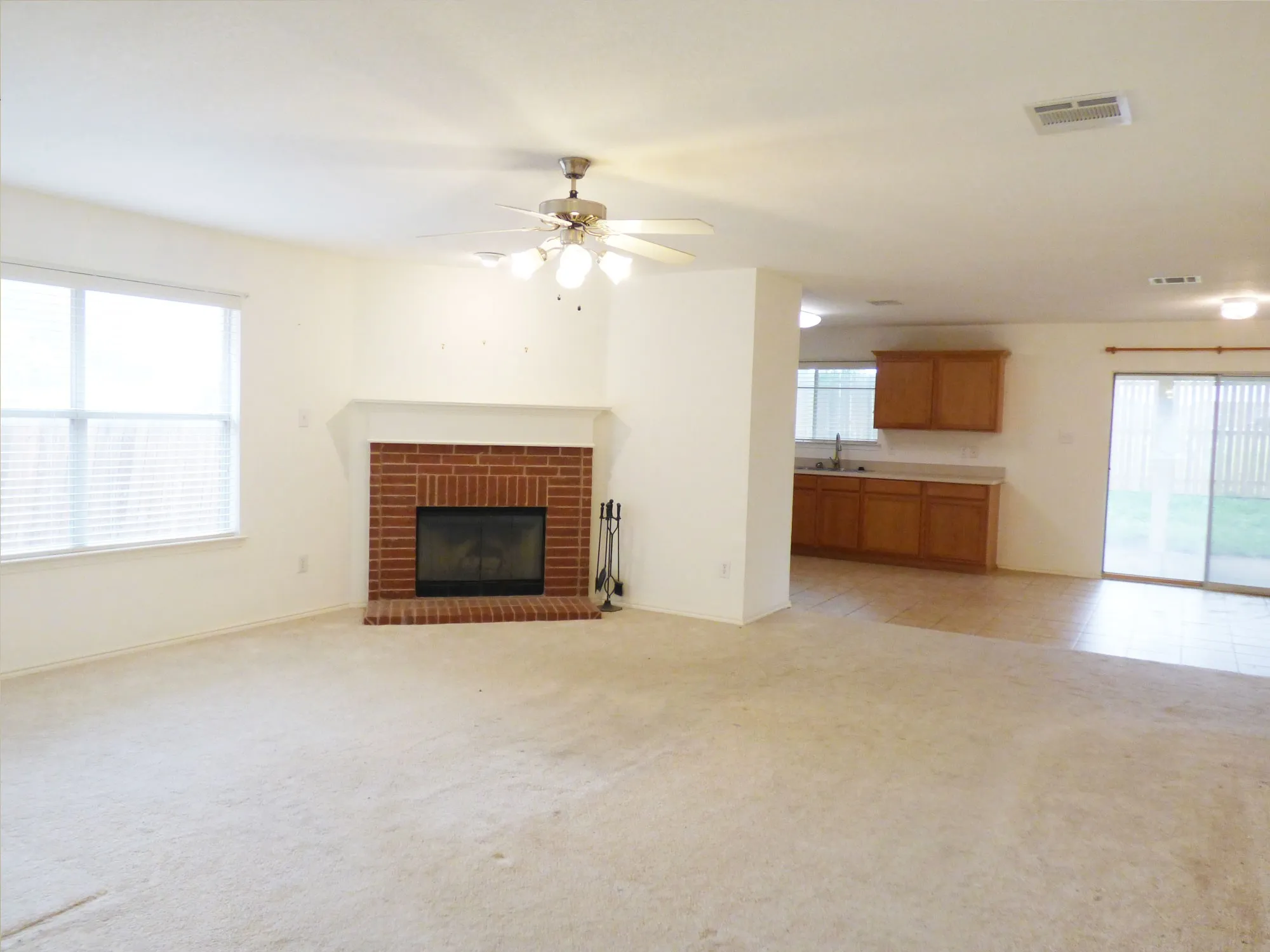 Living room featuring a brick fireplace, ceiling fan, and carpeted flooring