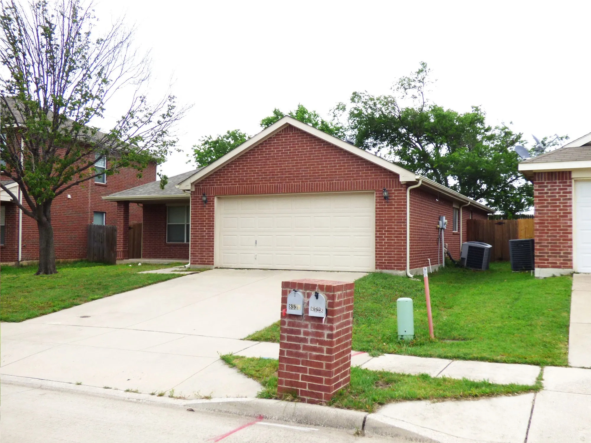 Brick exterior with an attached garage, featuring a concrete driveway and sidewalk