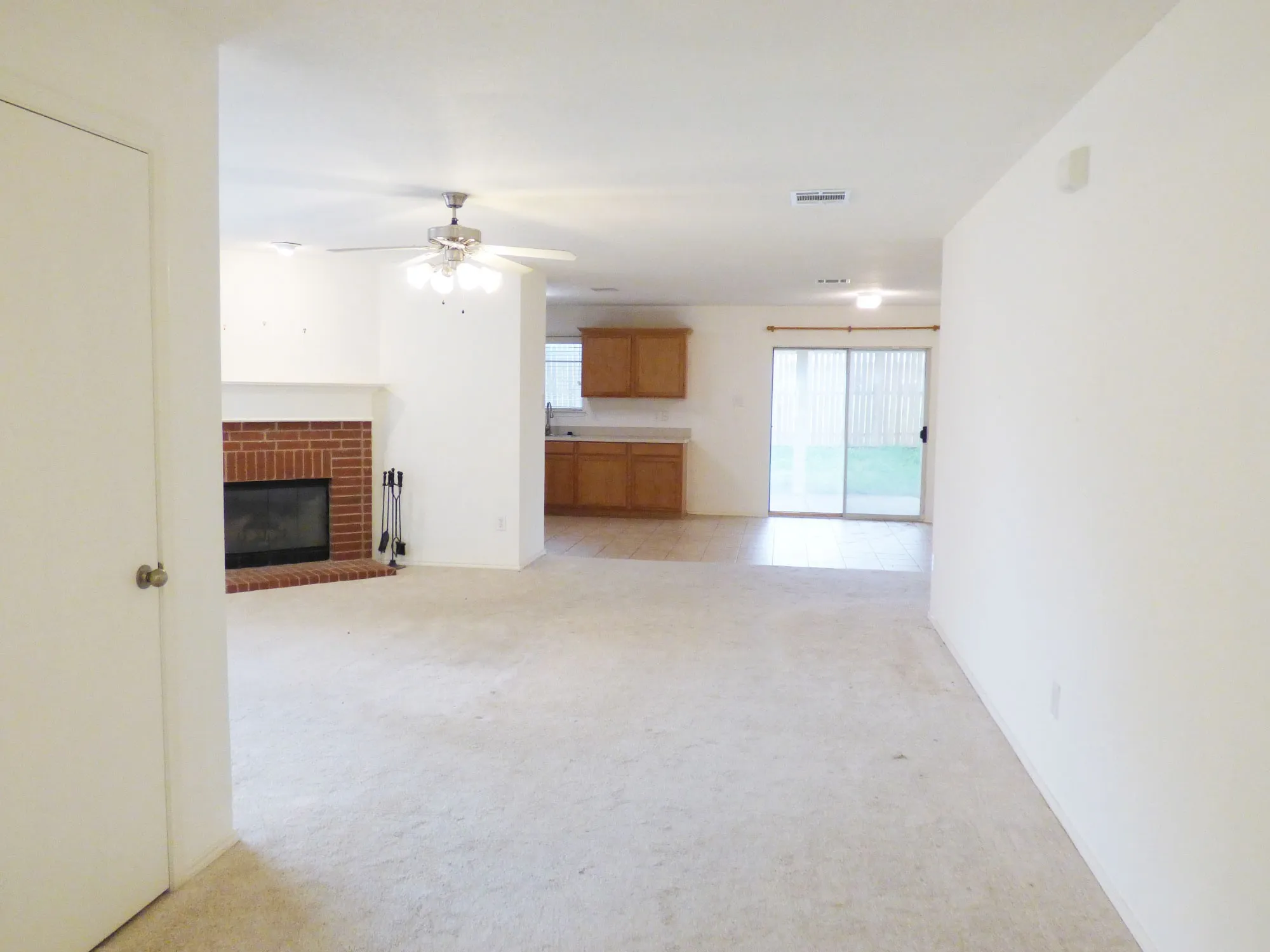 Spacious interior featuring light-toned carpeting and a brick fireplace