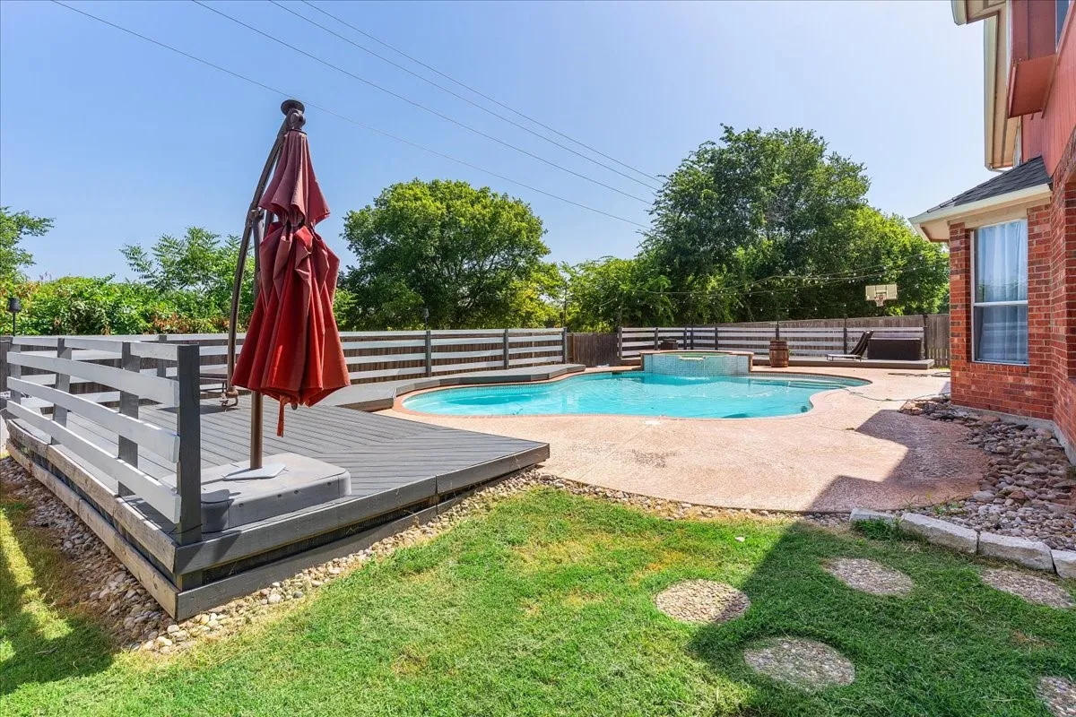 Backyard featuring a freeform swimming pool, integrated spa, and a composite deck with built-in railing