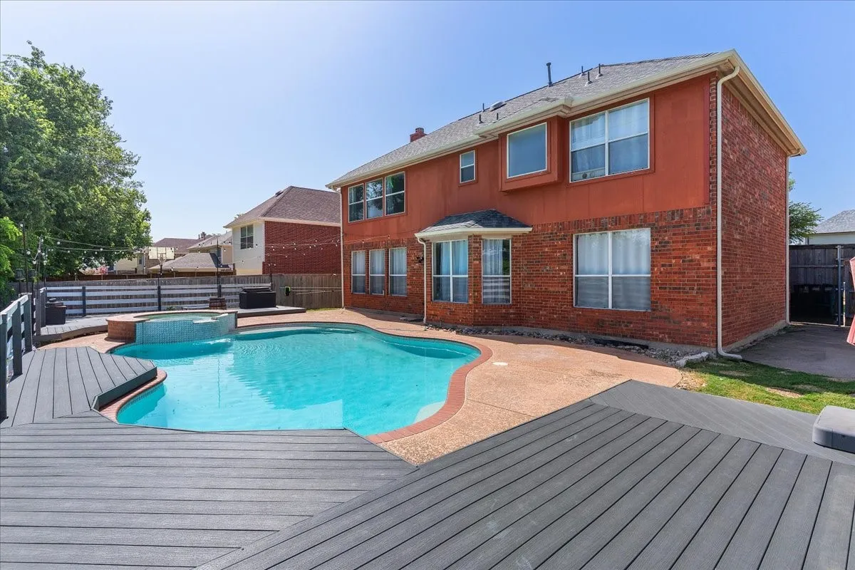 Backyard oasis featuring a freeform swimming pool, integrated spa, and expansive multi-level composite decking