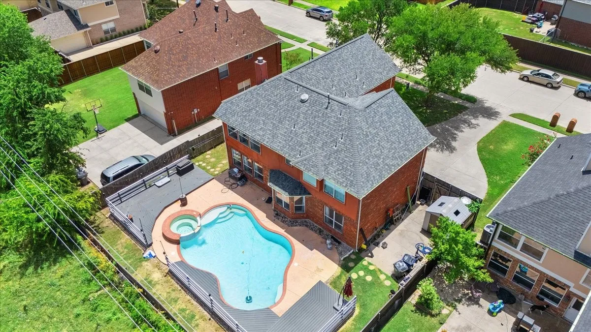 Brick exterior residence featuring a private backyard with a freeform swimming pool and integrated spa