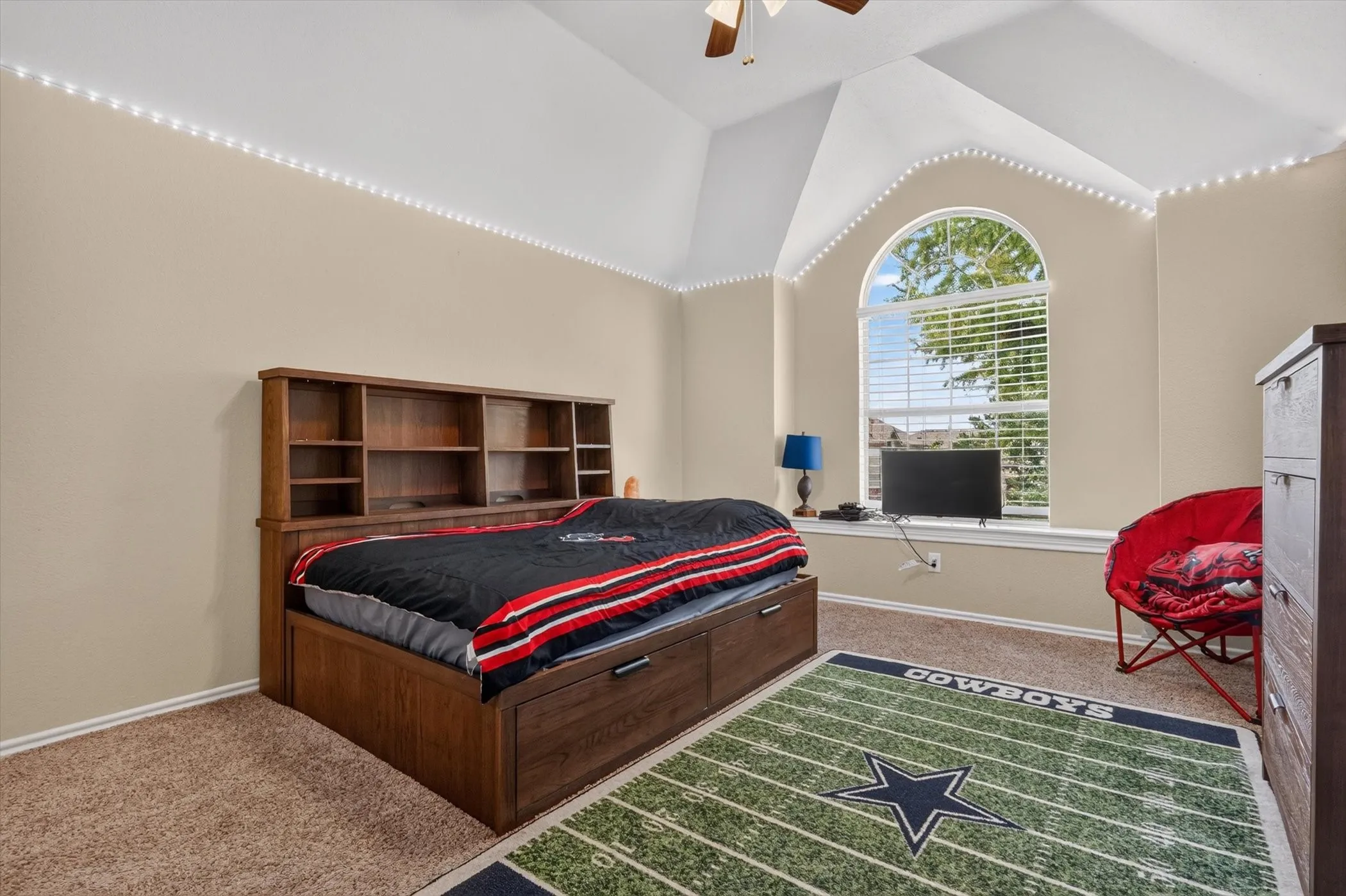 Bedroom featuring a vaulted ceiling, arched window with blinds, and neutral-toned walls
