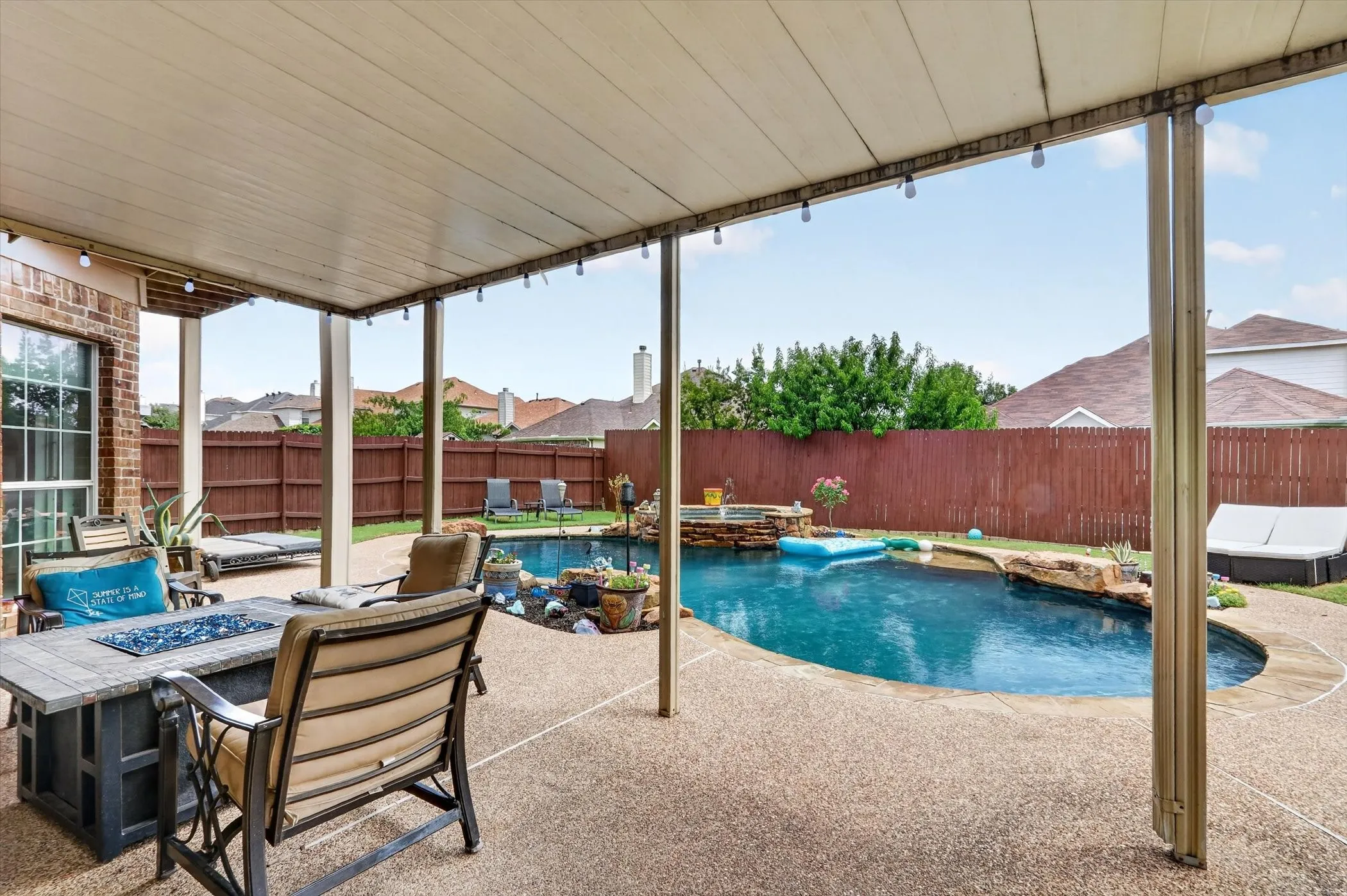 Covered patio featuring a ceiling fan, string lighting, and an aggregate concrete surface