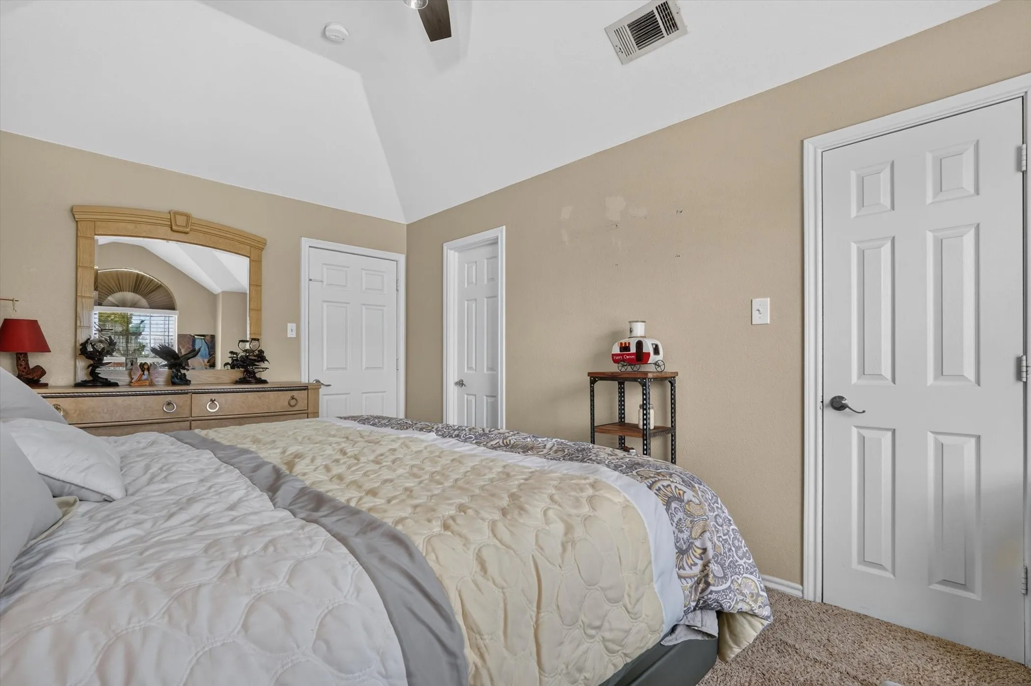 Vaulted ceiling bedroom featuring beige walls and white trim