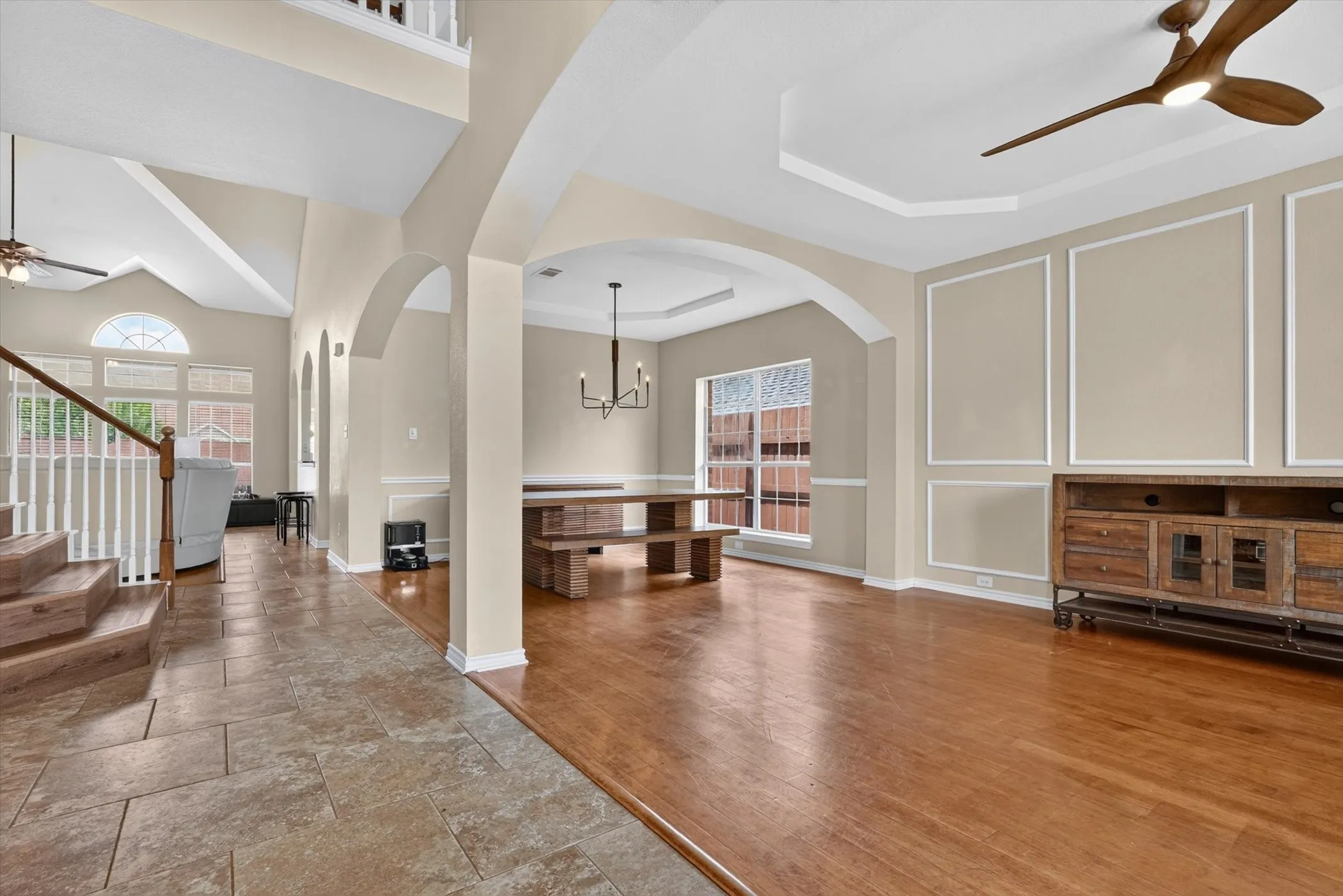 Spacious interior featuring a tiled entryway, wood-finish flooring, arched doorways, a high vaulted ceiling, and decorative wall molding