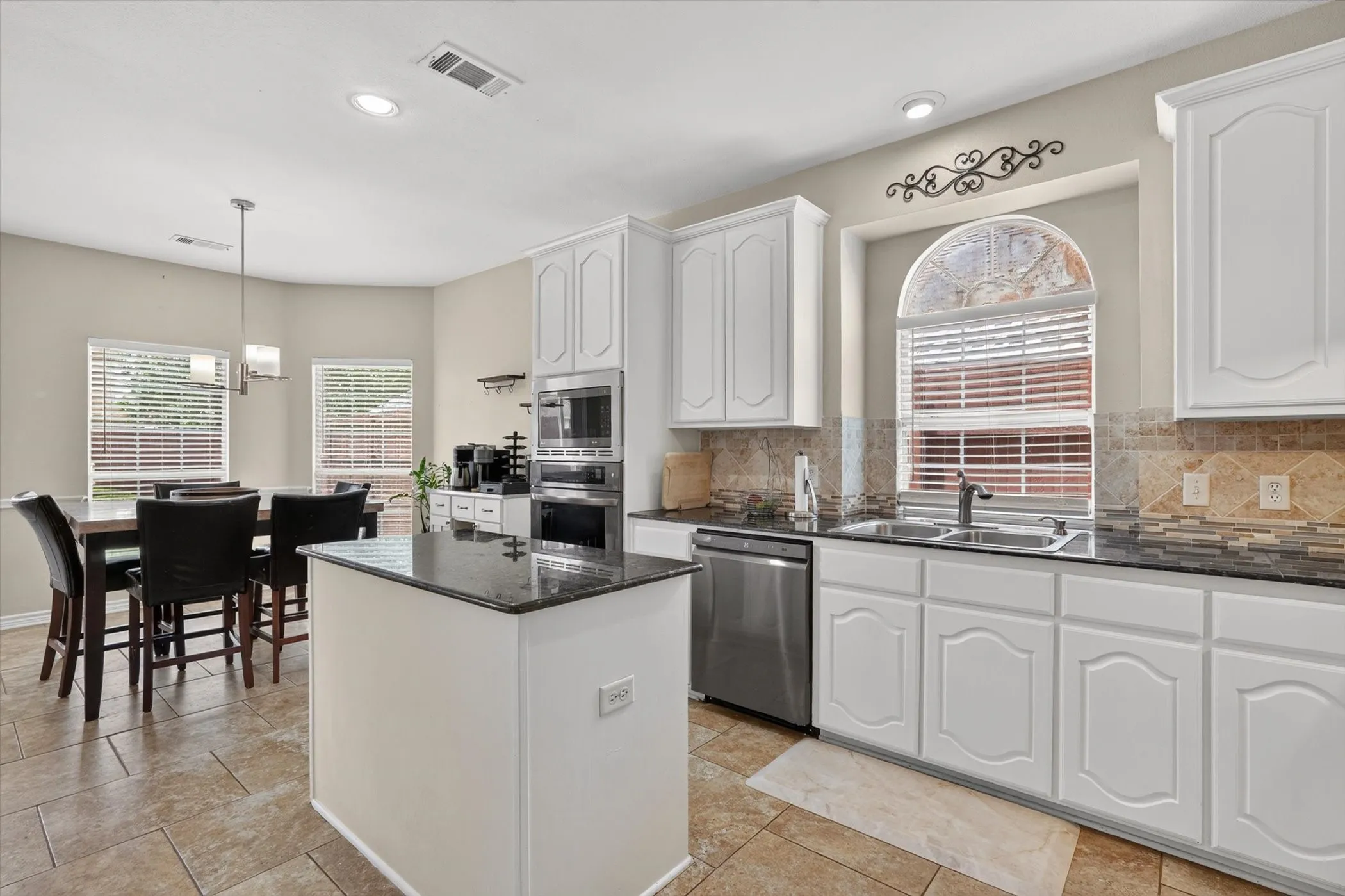Kitchen featuring white cabinetry, dark stone countertops, stainless steel appliances, and a tile backsplash