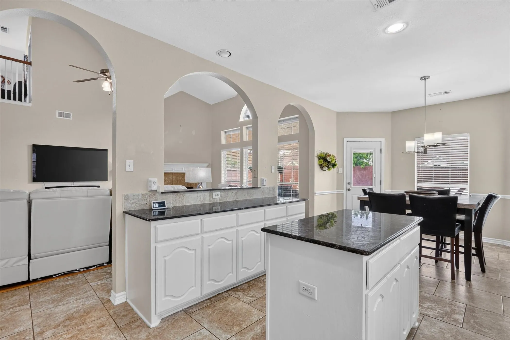 Kitchen with a white cabinetry island, dark granite countertops, and tile flooring