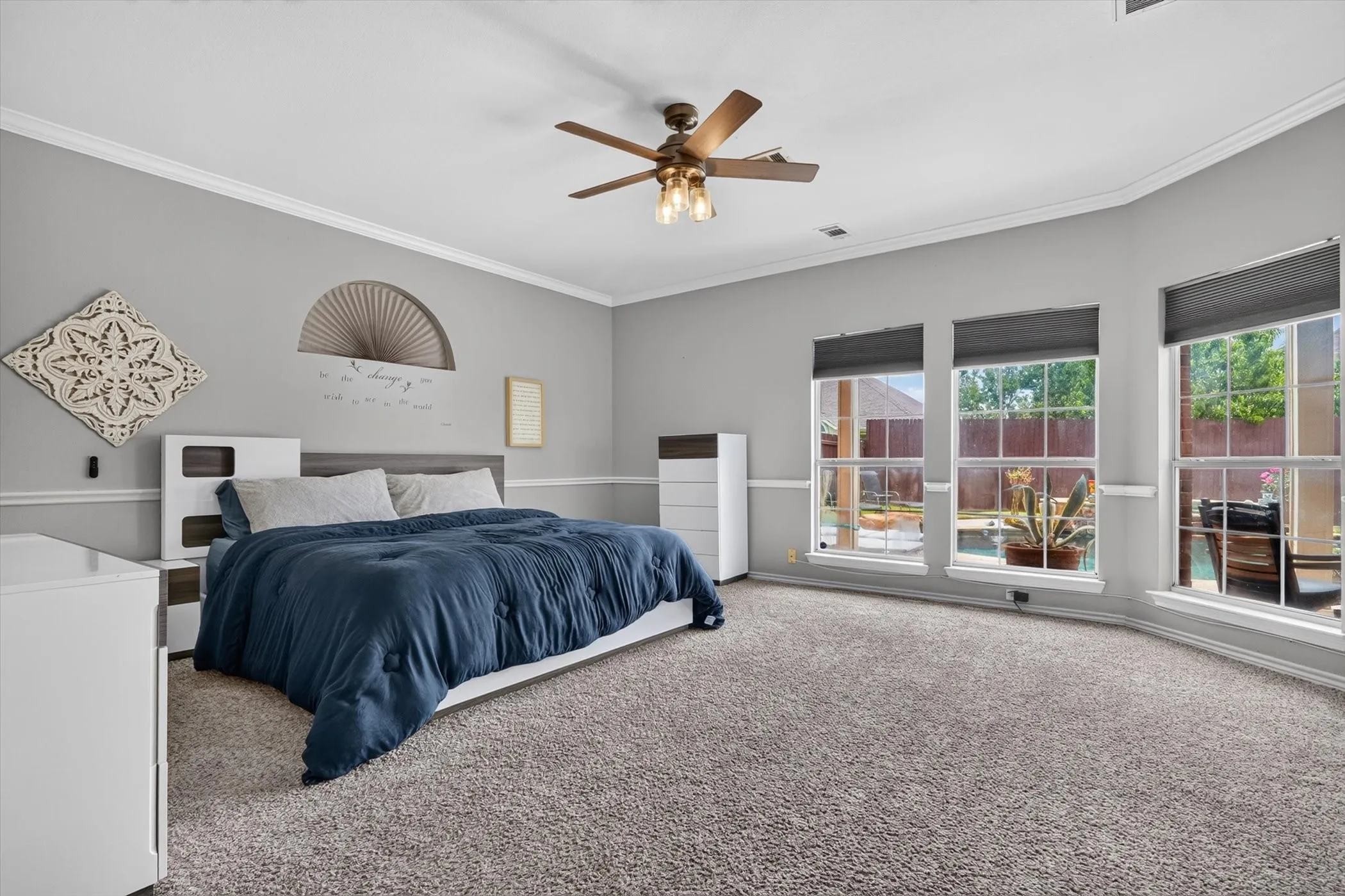 Spacious room with gray textured carpeting, multiple windows, and a ceiling fan with integrated lighting
