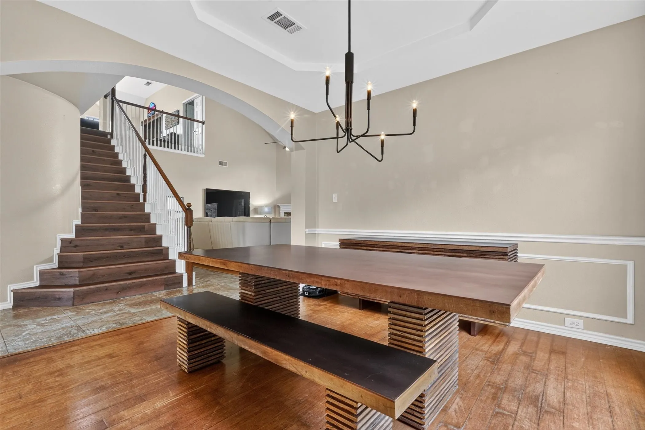 Dining area featuring a modern chandelier, wall molding, and wood-finish flooring