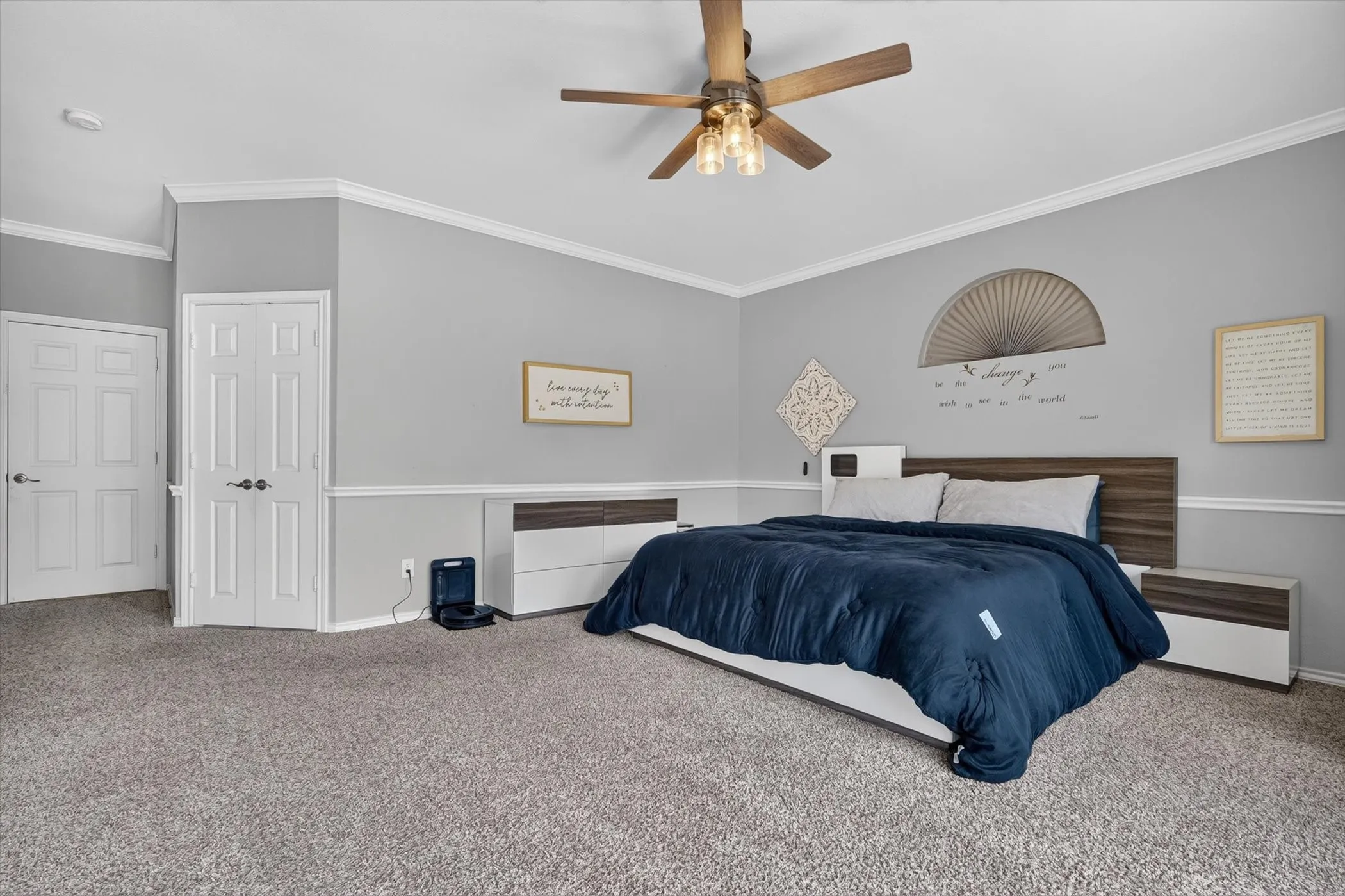 Carpeted room featuring a ceiling fan with integrated lighting, two panel doors, and two-tone wall treatment with crown molding