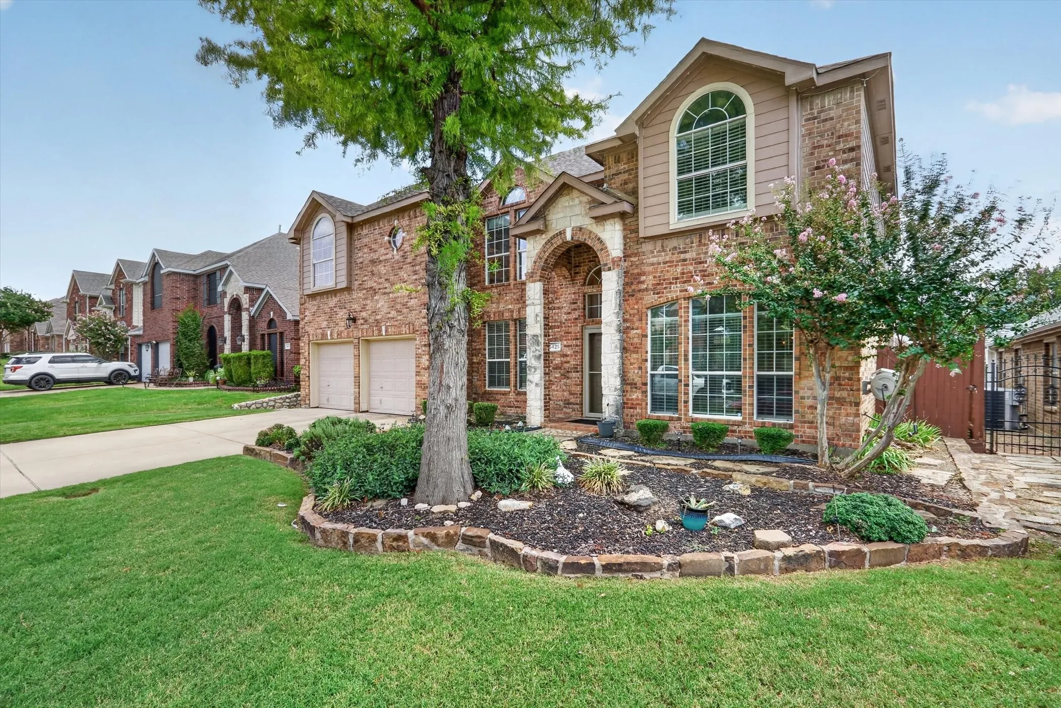Brick exterior with stone accents, arched entryway, and a two-car garage