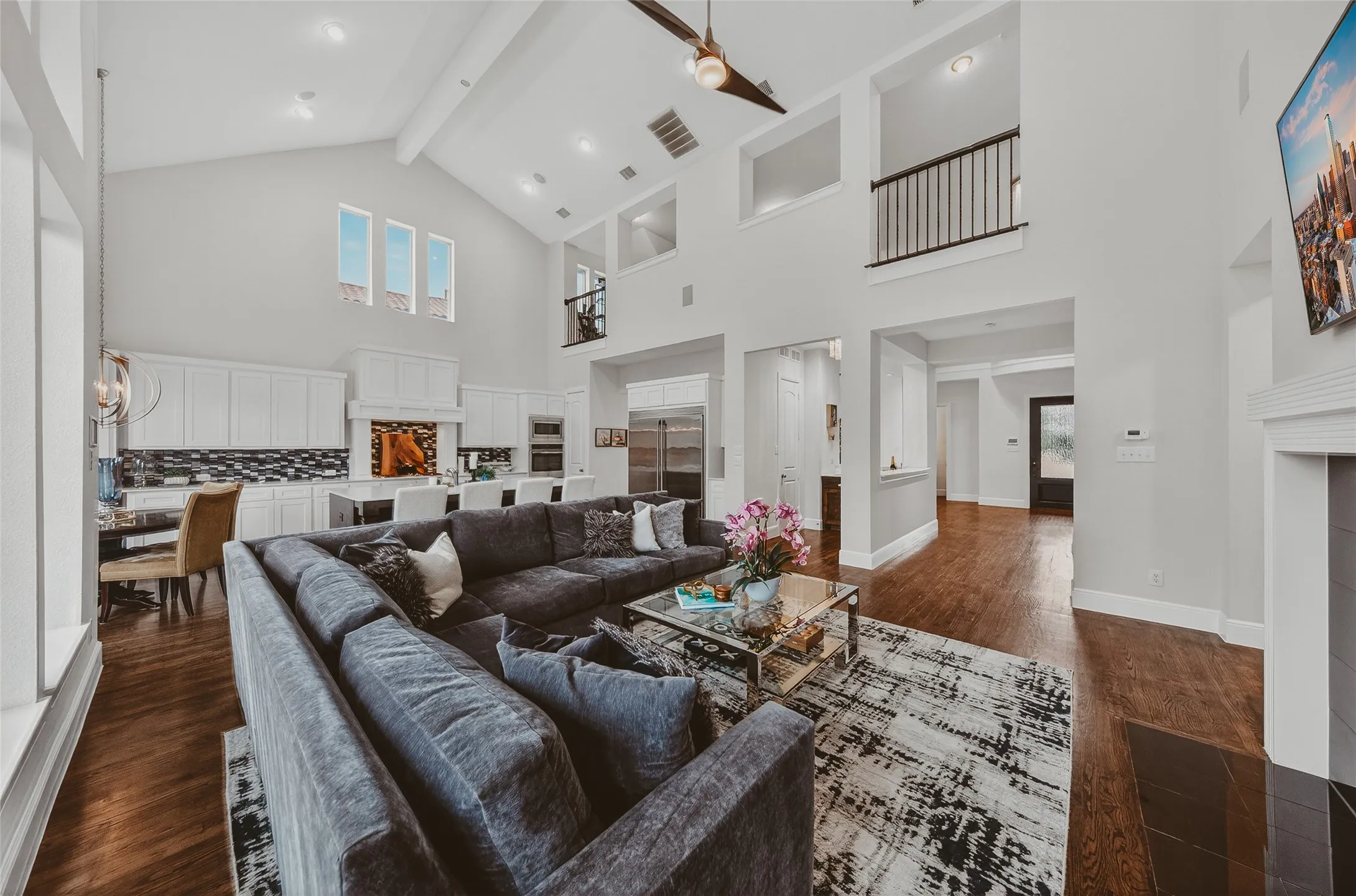Vaulted ceiling great room featuring wood-finish flooring, a contemporary ceiling fan, and an open-concept kitchen with white cabinetry and an island