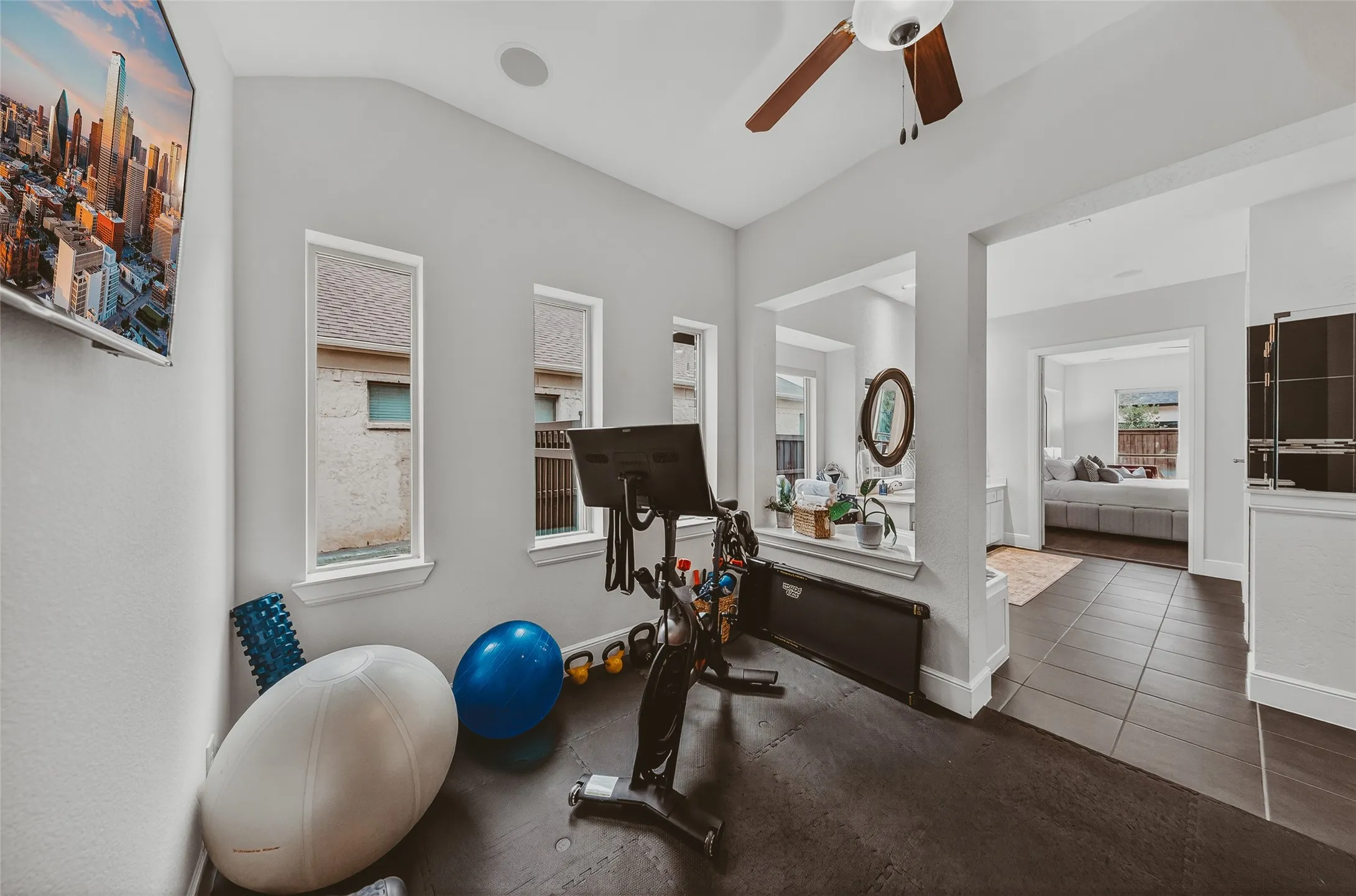 Interior space featuring a vaulted ceiling with a ceiling fan, two vertical windows, and dark tile flooring