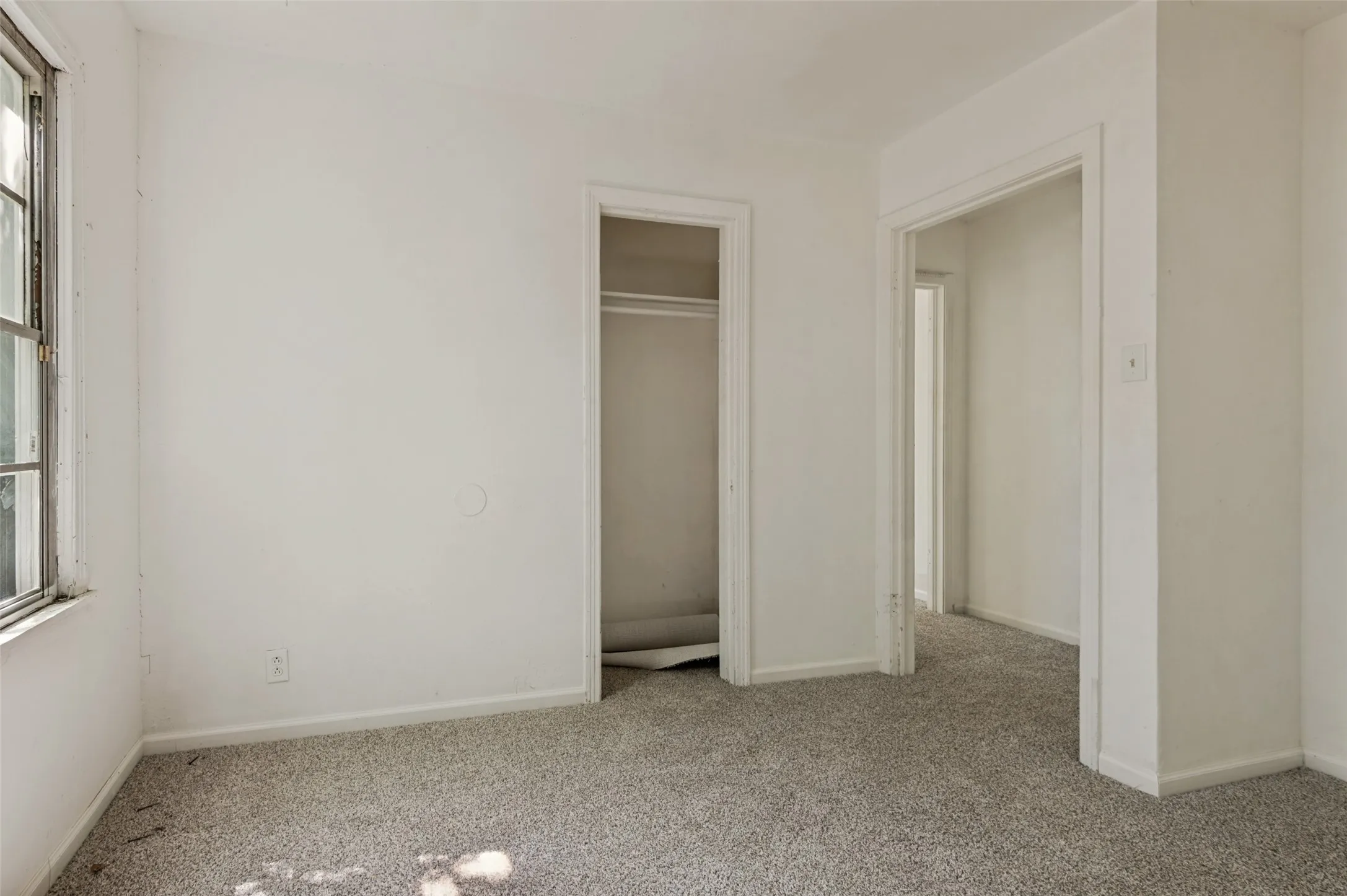 Carpeted room featuring a single window, white walls, and two doorways