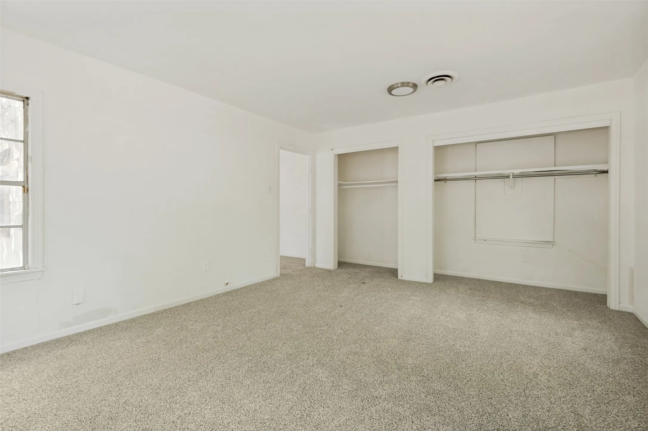 Carpeted interior space featuring white walls and a window with multiple panes
