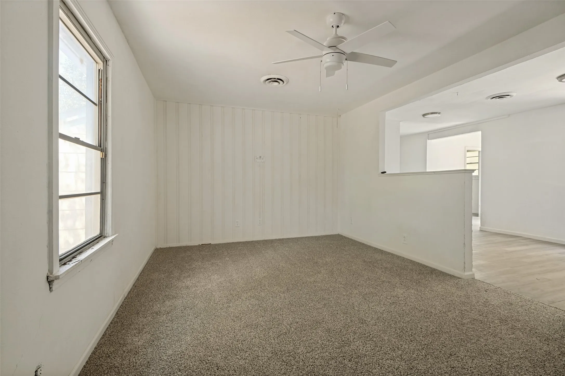 Carpeted room featuring a single window and a ceiling fan